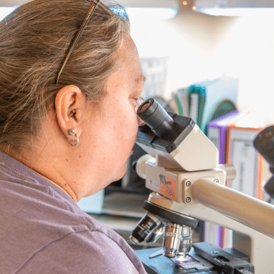Oncology professional looking into microscope, representing cancer treatment in virginia