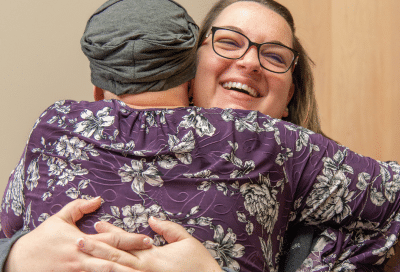 Cancer patient embracing a woman in support, representing emotional toll of cancer