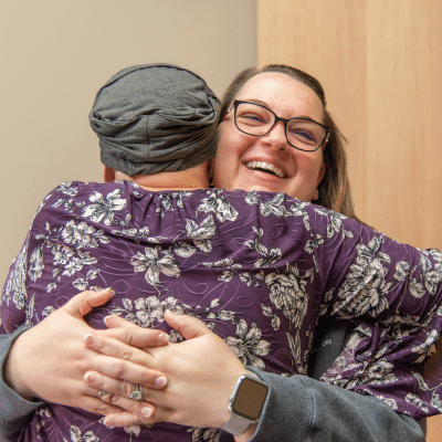Cancer patient embracing a woman in support, representing emotional toll of cancer