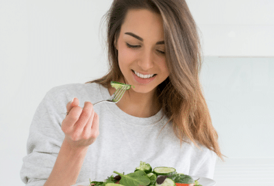 Woman enjoying a healthy salad, representing how to lower cancer risk naturally