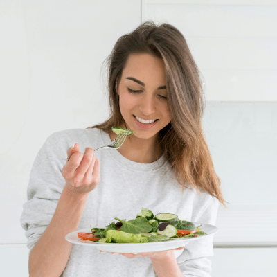 Woman enjoying a healthy salad, representing how to lower cancer risk naturally